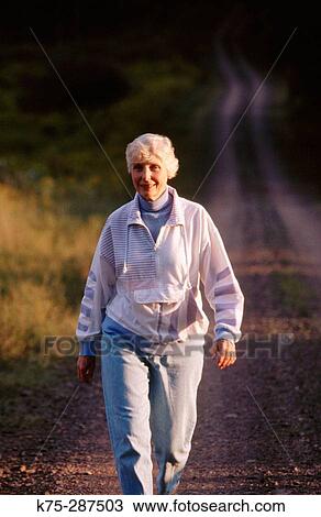Senior woman walking country road View Large Photo Image Stock Image - Senior woman walking country road. Fotosearch