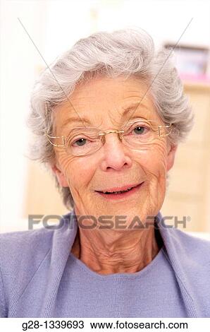 senior woman wearing glasses and a mauve cardigan smiling at home View Large Photo Image Stock Image - senior woman wearing glasses and a mauve cardigan smiling at home. Fotosearch