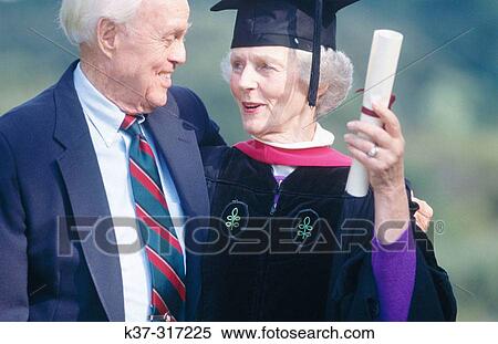 Senior woman wearing graduation cap and gown being congratulated by her husband on receiving degree View Large Photo Image Stock Photography - Senior woman wearing graduation cap and gown being congratulated by her husband on receiving degree. Fotosearch