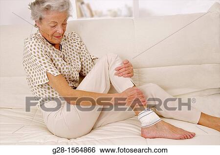 Senior woman with a bandaged ankle sitting on a sofa View Large Photo Image Stock Photograph - Senior woman with a bandaged ankle sitting on a sofa. Fotosearch