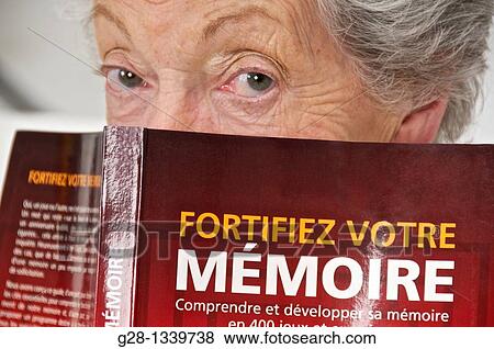 Stock Photo - senior woman with a book on how to exercise memory. Fotosearch