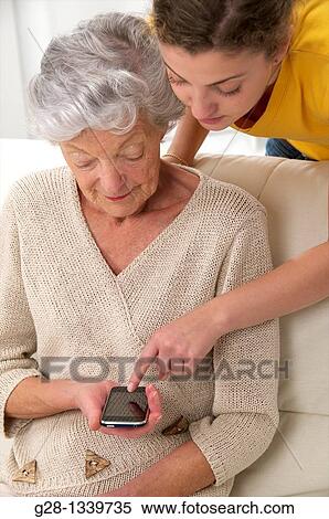 senior woman with a young woman who helps her using a portable phone View Large Photo Image Stock Photography - senior woman with a young woman who helps her using a portable phone. Fotosearch