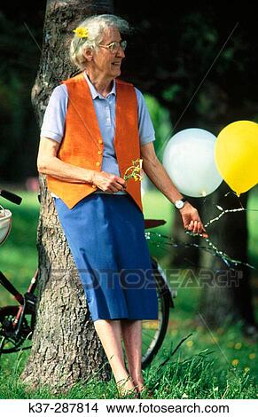 Senior woman with bike and balloons in park View Large Photo Image Picture - Senior woman with bike and balloons in park. Fotosearch