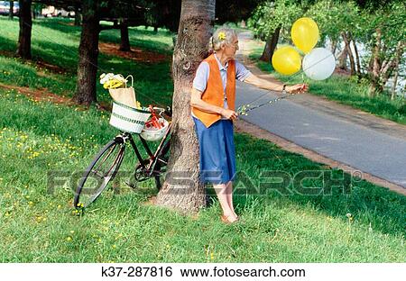 Senior woman with bike and balloons in park View Large Photo Image Stock Photograph - Senior woman with bike and balloons in park. Fotosearch