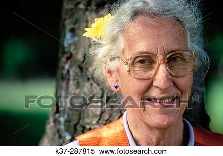 Stock Photography - Senior woman with flower in hair and glasses. Fotosearch