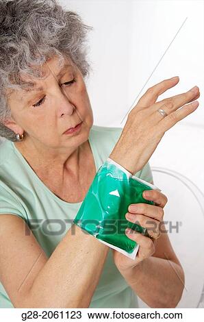 Senior woman with grey hair applying a green cold or hot gel compress to relieve pain around her arm and wrist View Large Photo Image Stock Image - Senior woman with grey hair applying a green cold or hot gel compress to relieve pain around her arm and wrist. Fotosearch