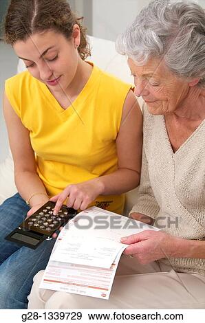 senior woman with medical papers in hand with a young woman who helps her counting with a mini calculator View Large Photo Image Stock Photo - senior woman with medical papers in hand with a young woman who helps her counting with a mini calculator. Fotosearch