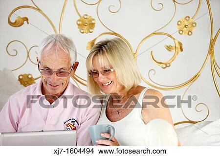 Seniors on bed using laptop computer View Large Photo Image Picture - Seniors on bed using laptop computer. Fotosearch