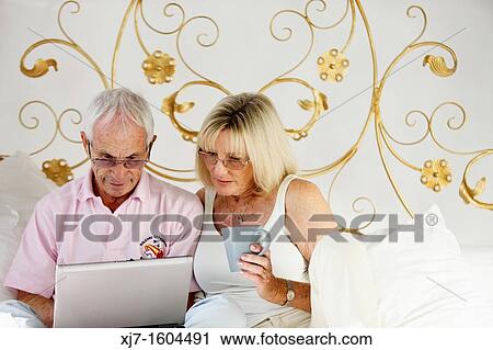 Seniors on bed using laptop computer View Large Photo Image Stock Image - Seniors on bed using laptop computer. Fotosearch