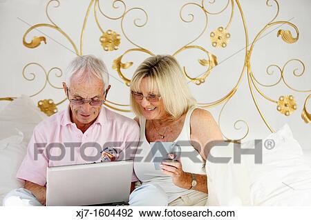 Seniors on bed using laptop computer View Large Photo Image Stock Image - Seniors on bed using laptop computer. Fotosearch