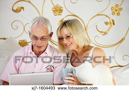 Seniors on bed using laptop computer View Large Photo Image Stock Image - Seniors on bed using laptop computer. Fotosearch