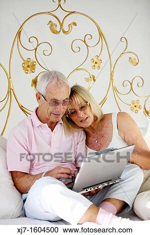 Seniors on bed using laptop computer View Large Photo Image Stock Image - Seniors on bed using laptop computer. Fotosearch