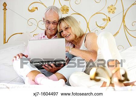Seniors on bed using laptop computer View Large Photo Image Stock Photo - Seniors on bed using laptop computer. Fotosearch