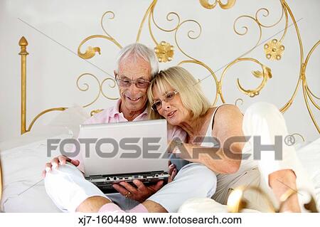 Seniors on bed using laptop computer View Large Photo Image Stock Photo - Seniors on bed using laptop computer. Fotosearch