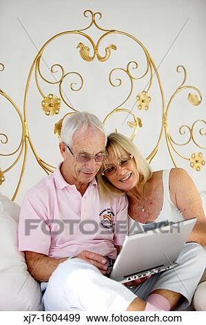 Stock Photo - Seniors on bed using laptop computer. Fotosearch