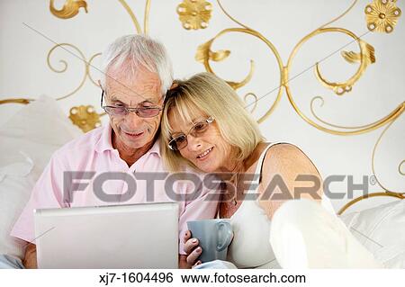 Seniors on bed using laptop computer View Large Photo Image Stock Photograph - Seniors on bed using laptop computer. Fotosearch