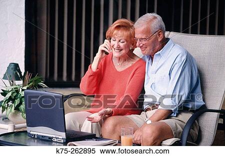 Seniors using laptop and cell phone View Large Photo Image Stock Photography - Seniors using laptop and cell phone. Fotosearch