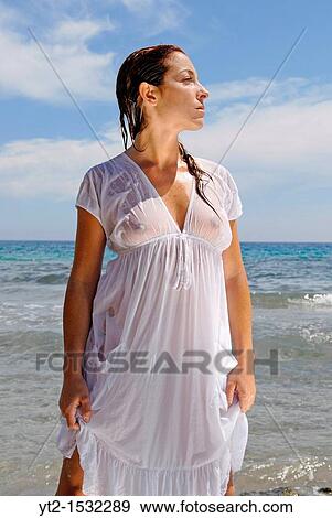 Sensual and attractive red haired girl on the beach, wearing a wet
