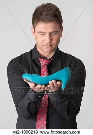 Serious adult male with black shirt and red tie holds blue womans shoe View Large Photo Image Stock Photo - Serious adult male with black shirt and red tie holds blue womans shoe. Fotosearch