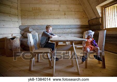 Picture - Serious Emorional Kids, Boy and Girl Sitting at Wooden Table in Old Blockhouse. Fotosearch