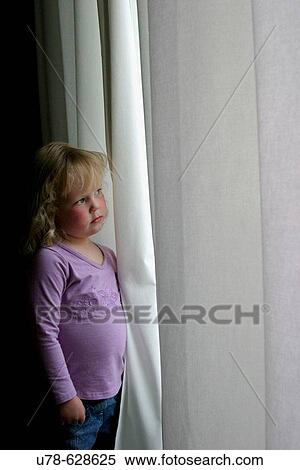 Serious young girl peering out of window View Large Photo Image Stock Photography - Serious young girl peering out of window. Fotosearch
