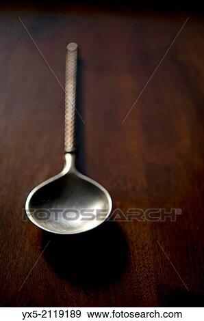 Stock Photo - Serving spoon on a dark wood table.. Fotosearch