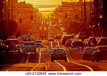 Stock Photo - Setting sun shines on afternoon traffic on Taraval Street in San Francisco. Note trolley tracks.. Fotosearch