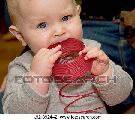 Seven month old baby chewing on a plastic slinky toy. View Large Photo Image Stock Image - Seven month old baby chewing on a plastic slinky toy.. Fotosearch
