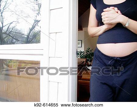 Stock Photography - Seven-month pregnant woman coming out of her house. Fotosearch