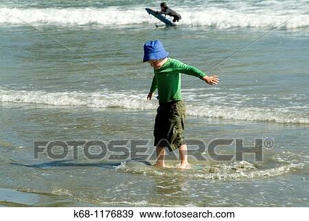 seven year old boy playing with a skim board on the beach near Tofino, West Coast, Vancouver Island, British Columbia, Canada View Large Photo Image Stock Photo - seven year old boy playing with a skim board on the beach near Tofino, West Coast, Vancouver Island, British Columbia, Canada. Fotosearch