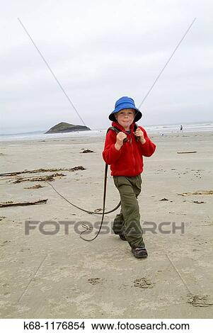 Picture - seven year old boy plays on beach near Tofino, West Coast, Vancouver Island, British Columbia, Canada. Fotosearch