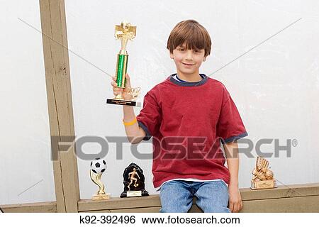 Seven year old boy with his athletic trophies View Large Photo Image Stock Photograph - Seven year old boy with his athletic trophies. Fotosearch