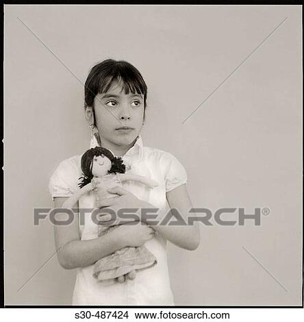 Seven year old girl with far away look in her eyes clutching a rag doll View Large Photo Image Picture - Seven year old girl with far away look in her eyes clutching a rag doll. Fotosearch