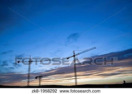 Several cranes abandoned at the sunset in a construction of buildings, Spain. View Large Photo Image Stock Image - Several cranes abandoned at the sunset in a construction of buildings, Spain.. Fotosearch