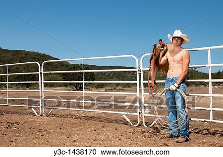 Sexy cowboy with saddle on a ranch View Large Photo Image Stock Image - Sexy cowboy with saddle on a ranch. Fotosearch