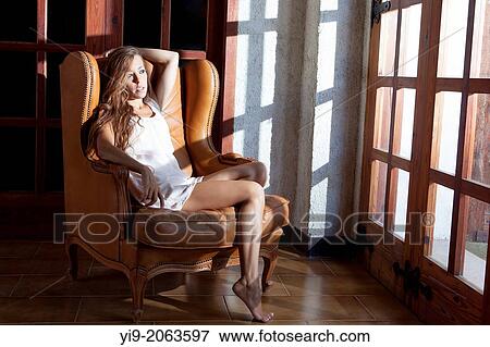 Stock Photo - sexy girl sitting on a chair looking through the window.. Fotosearch