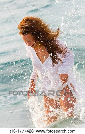 Stock Photo - Sexy young woman caught by a water wave. Fotosearch