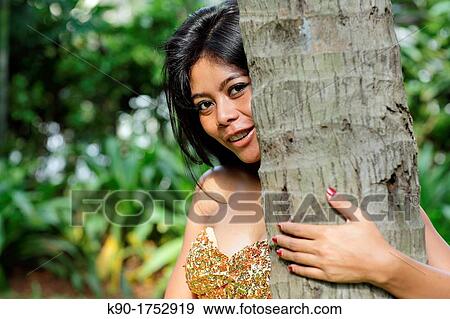 Sexy young woman, flirting, leaning agains tree trunk, Indonesia, Asia View Large Photo Image Stock Photo - Sexy young woman, flirting, leaning agains tree trunk, Indonesia, Asia. Fotosearch
