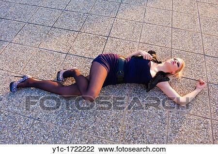 Stock Image - Sexy young woman is lying down on tarmac. Fotosearch