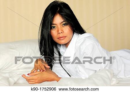 Stock Photograph - Sexy young woman, laying on bed, Indonesia, Asia. Fotosearch