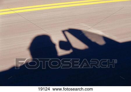 Picture - Shadow of convertible and driver on highway. Fotosearch