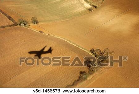 Stock Photo - shadow of the plane coming to landing at London Luton Airport, taken from this plane, beautiful fields like carpets down there. Fotosearch