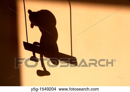 shadow of toy dog sitting on a swing on wall View Large Photo Image Picture - shadow of toy dog sitting on a swing on wall. Fotosearch