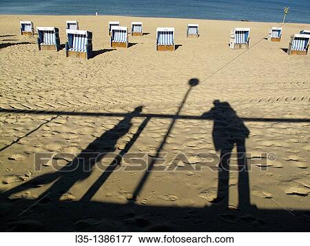 Stock Photo - Shadows of people on the beach of Westerland, beach chairs and the North Sea in the background, Sylt, Germany. Fotosearch