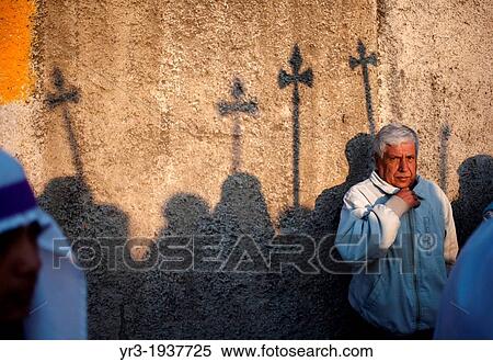 Stock Photography - Shadows of spears are cast in a wall as a man watches the Jesus Nazareno de la Merced procession during Easter Holy Week procession in Antigua Guatemala, Guatemala, March 29, 2013.. Fotosearch