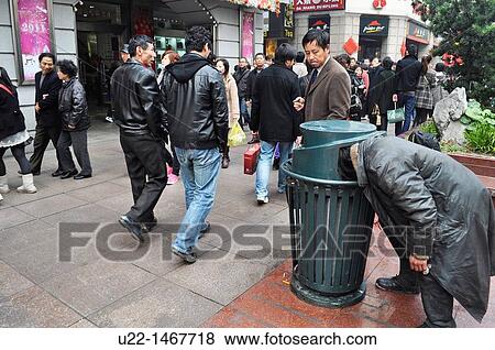 Shanghai (China): a homeless man looking for something to eat into a garbage can in East Nanjing Road View Large Photo Image Stock Photo - Shanghai (China): a homeless man looking for something to eat into a garbage can in East Nanjing Road. Fotosearch