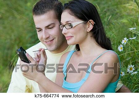 Sharing a handheld wireless device View Large Photo Image Picture - Sharing a handheld wireless device. Fotosearch