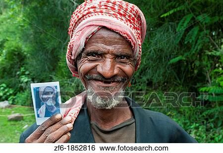 Stock Photograph - Shashemene Ethiopia Africa Alaba tribe portrait of local old man with red turban farmer proud of Fuji Polaroid of himself 9. Fotosearch