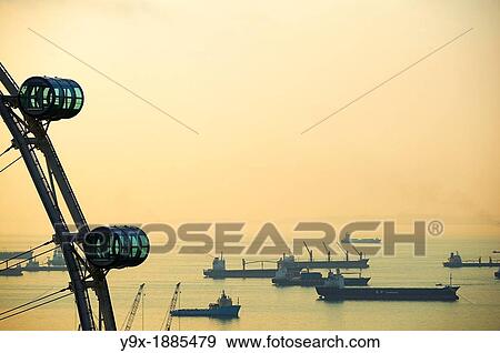 Stock Photo - Shipping boats and freighters at sunset off the coast of Singapore as seen through the Singapore Flyer. Fotosearch