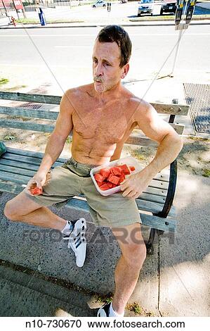Shirtless man eating pieces of watermelon from a plastic container. View Large Photo Image Stock Image - Shirtless man eating pieces of watermelon from a plastic container.. Fotosearch